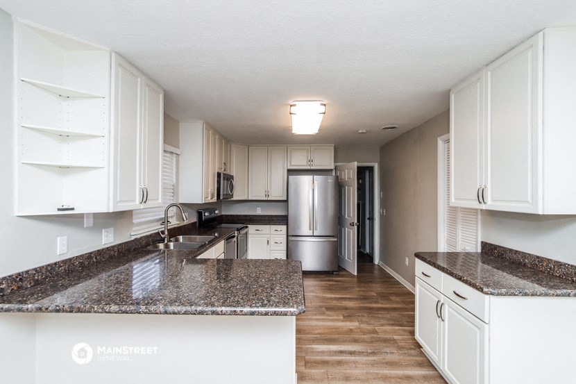 a kitchen with white cabinets and granite counter tops