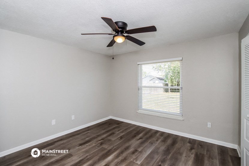 the spacious living room with a ceiling fan and a window