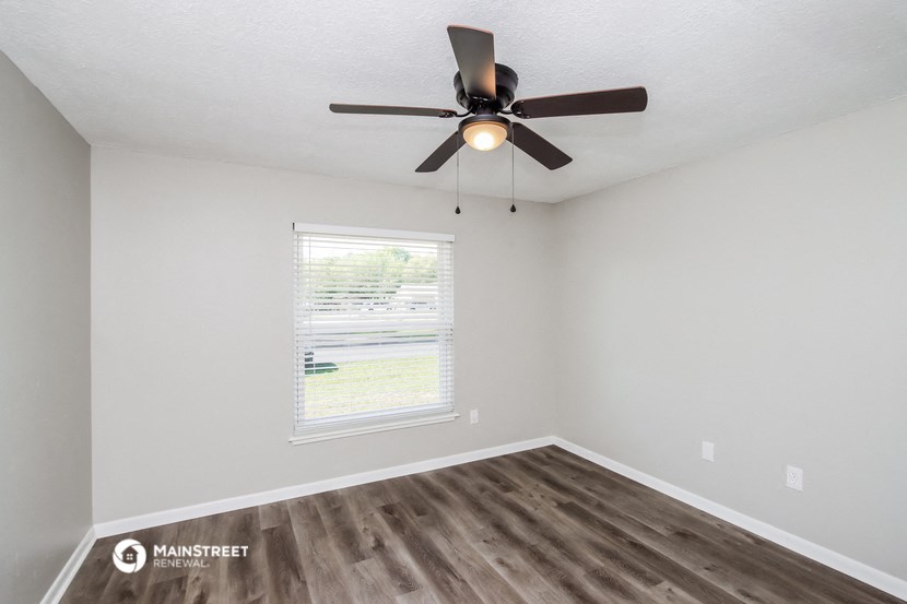 the spacious living room with a ceiling fan and a window
