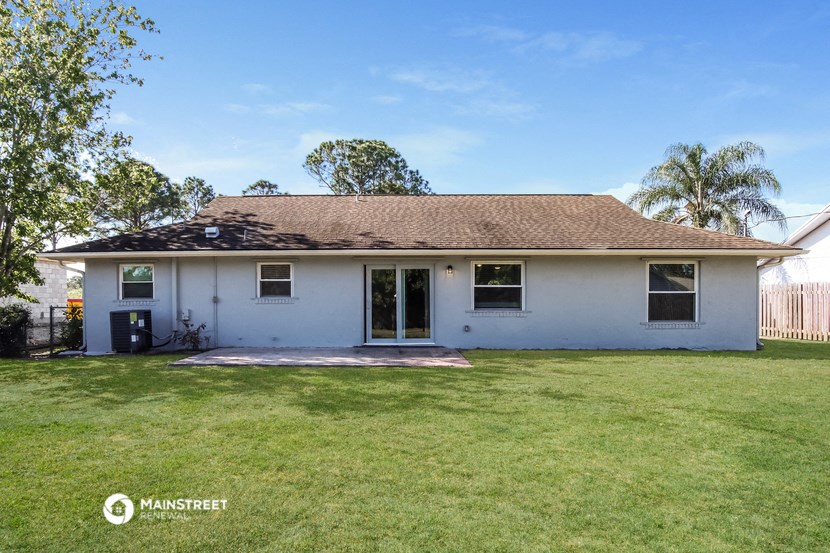 a white house with a grass yard and a tree