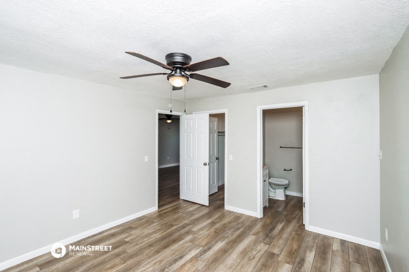 a living room with a ceiling fan and a door to a bathroom