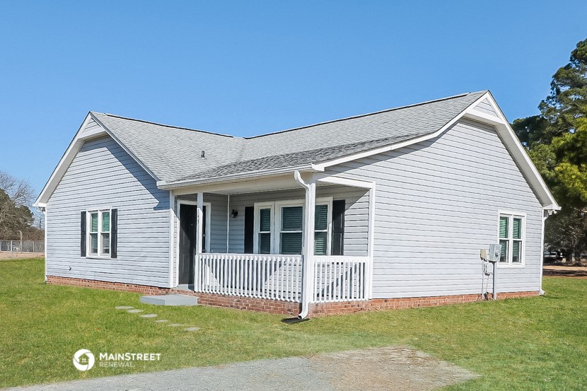 a small white house with a porch and a lawn