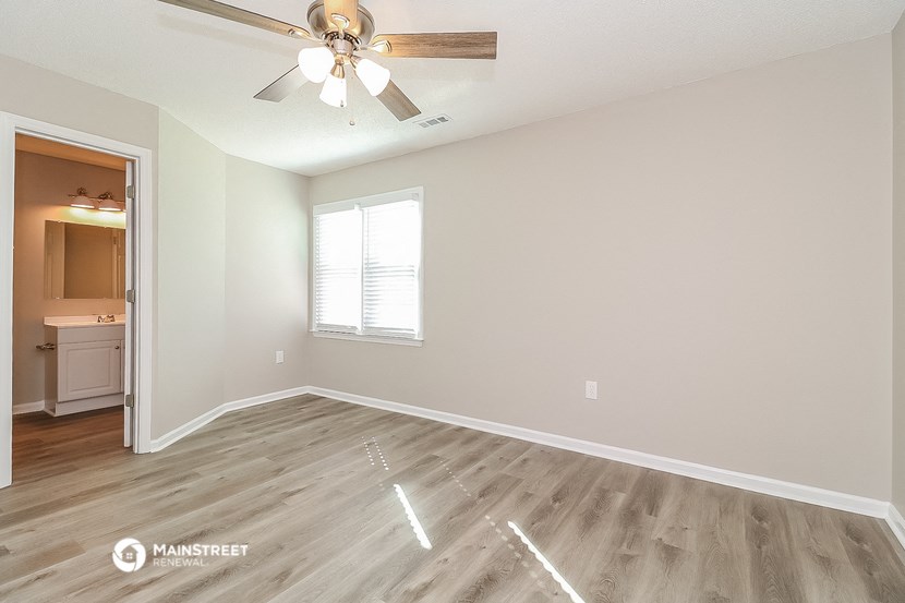 the spacious living room with hardwood flooring and a ceiling fan