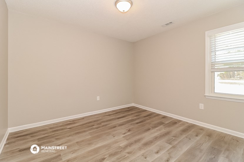 the spacious living room with wood flooring and a window