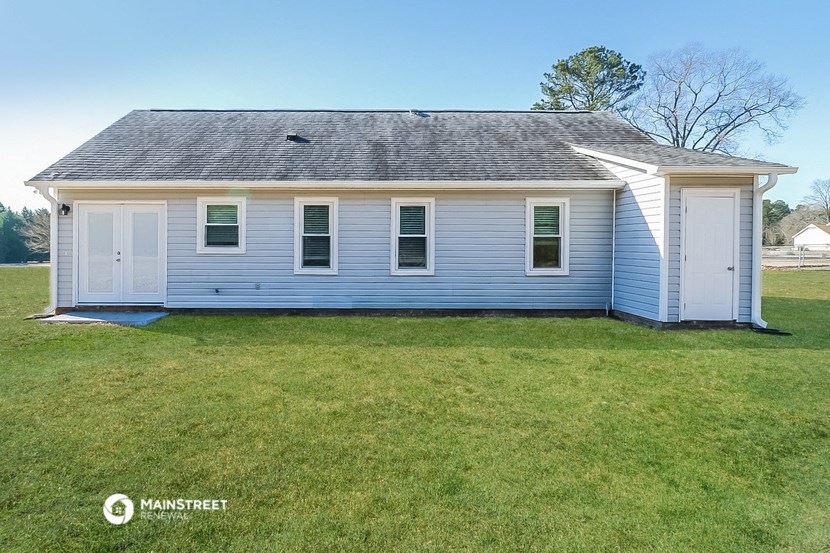 a white house with a gray roof on a grassy yard