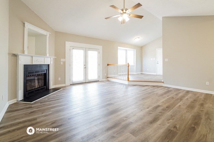 an empty living room with a fireplace and a ceiling fan