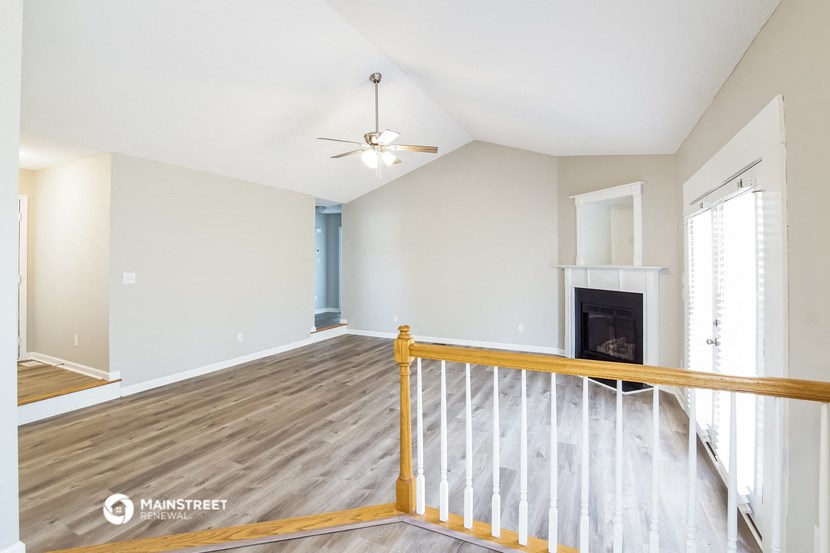 the living room and dining room of a house with wood floors and a fireplace