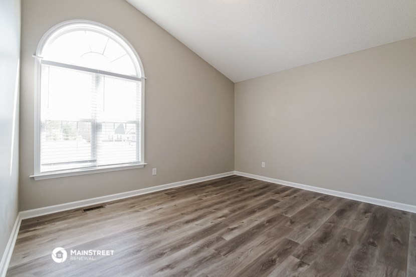 an empty room with wood flooring and a large window