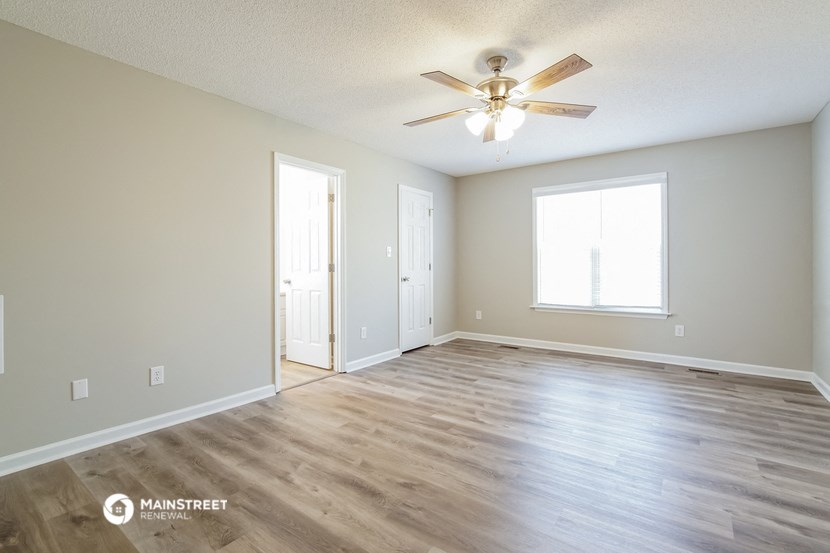 the spacious living room with hardwood floors and a ceiling fan