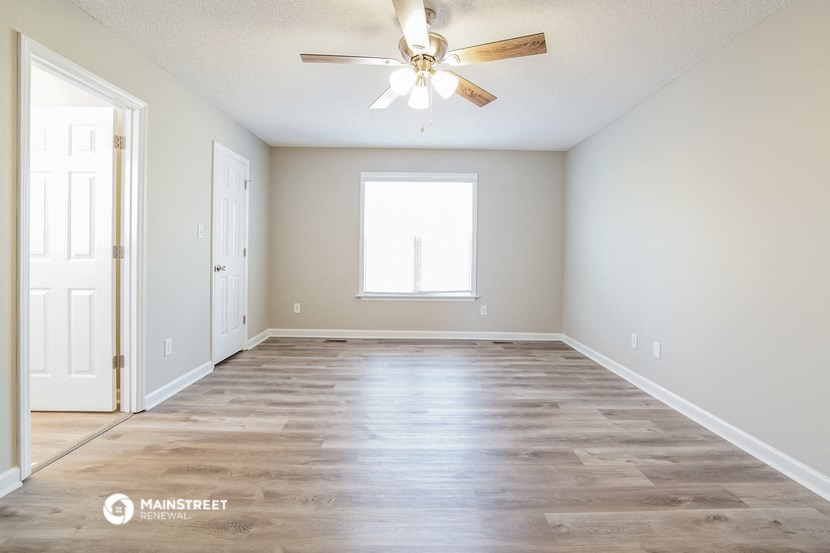 the spacious living room with hardwood floors and a ceiling fan