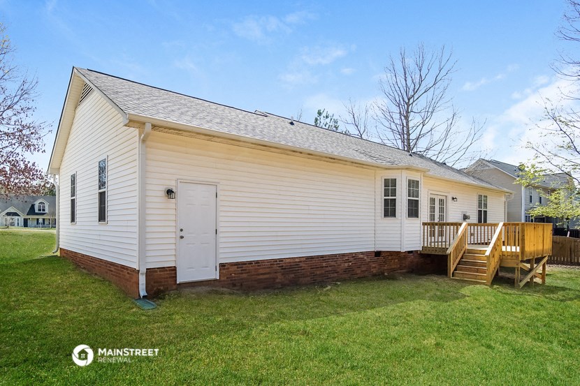 the front of a white house with a porch and a wooden deck