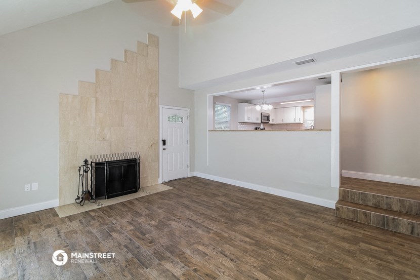 the living room with a fireplace and a kitchen in the background