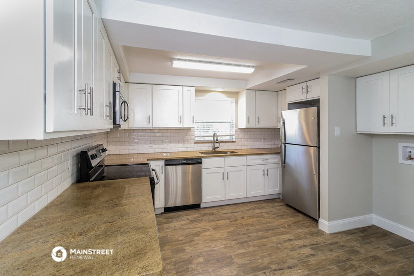 an empty kitchen with white cabinets and stainless steel appliances