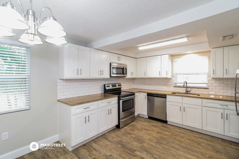 an empty kitchen with white cabinets and stainless steel appliances