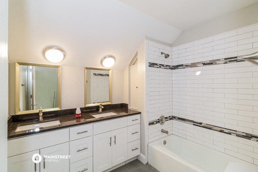 a white bathroom with a tub and a sink and a mirror