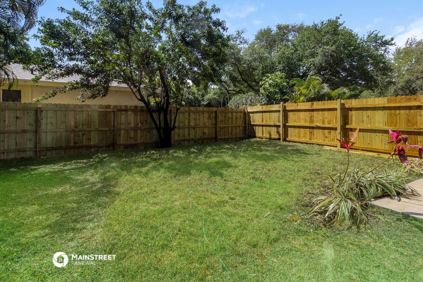 a backyard with a wooden fence and a tree
