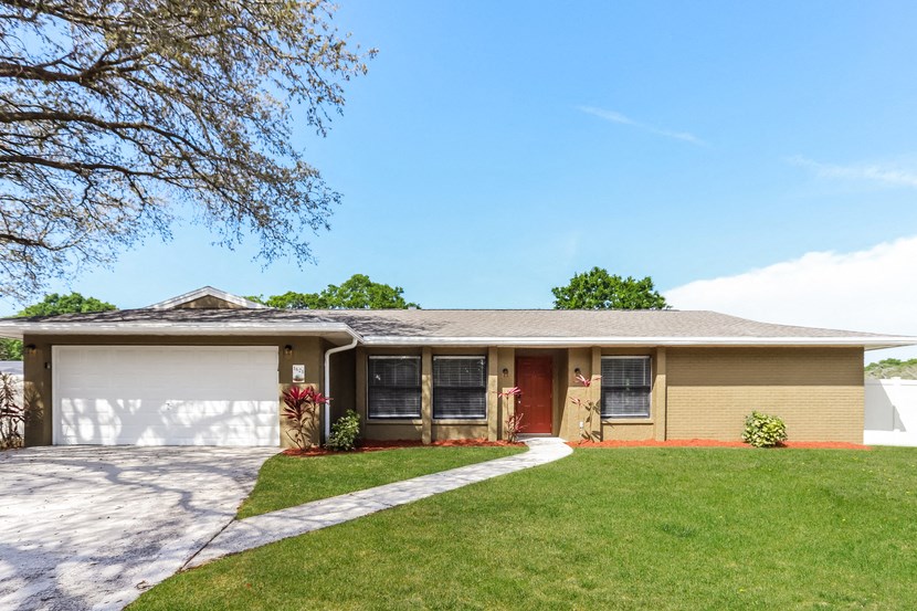 a yellow house with a driveway and a lawn