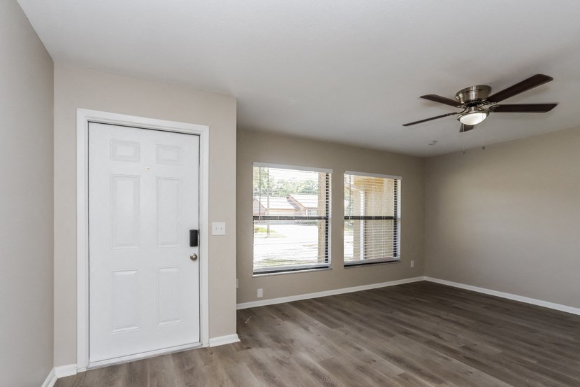 an empty living room with a ceiling fan and a window