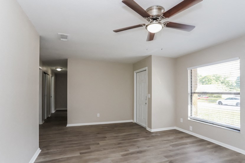 an empty living room with a ceiling fan and a window