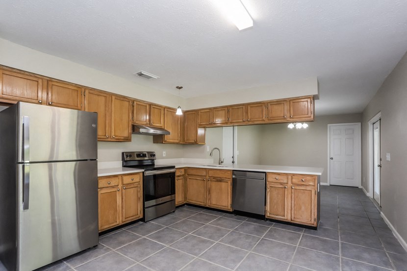 an empty kitchen with wooden cabinets and stainless steel appliances