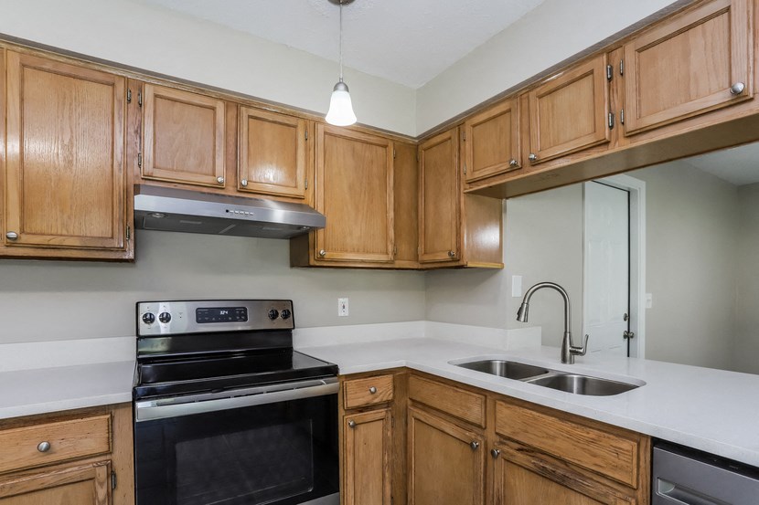 an empty kitchen with wooden cabinets and black appliances