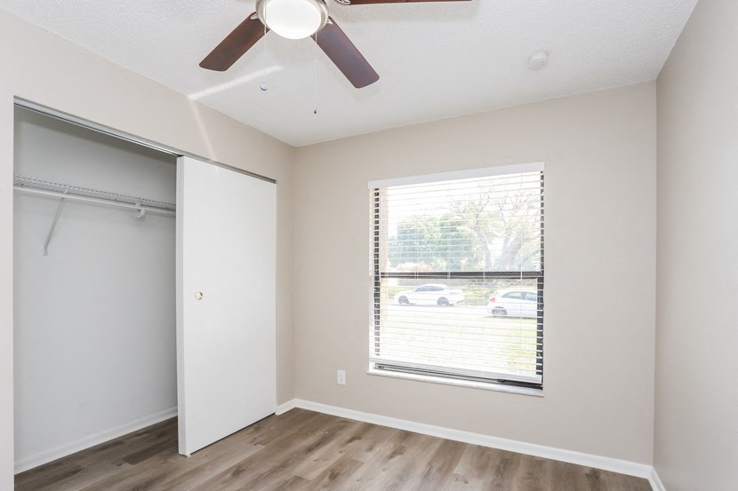 an empty bedroom with a window and a closet