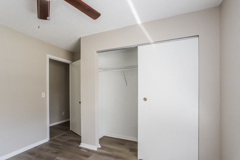 an empty bedroom with a closet and a ceiling fan