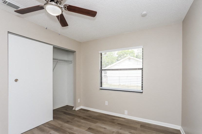 an empty bedroom with a window and a ceiling fan