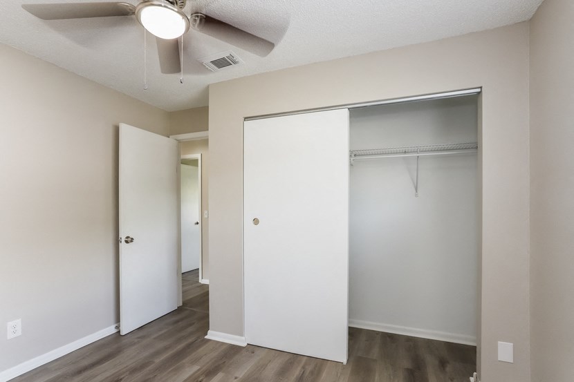 an empty bedroom with a closet and a ceiling fan