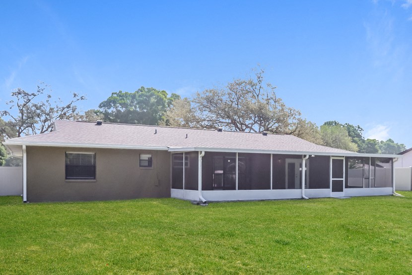 the back of a house with a grass yard and a blue sky