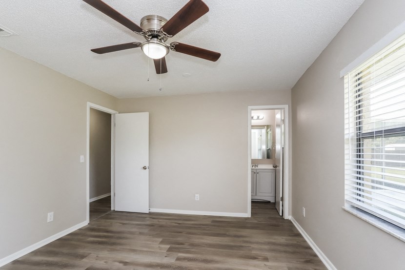 an empty living room with a ceiling fan and a bathroom