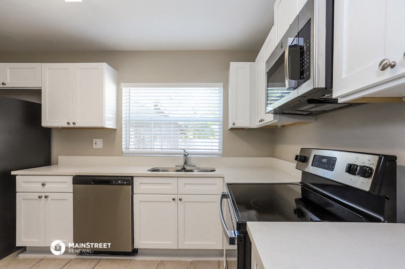 an empty kitchen with white cabinets and black appliances