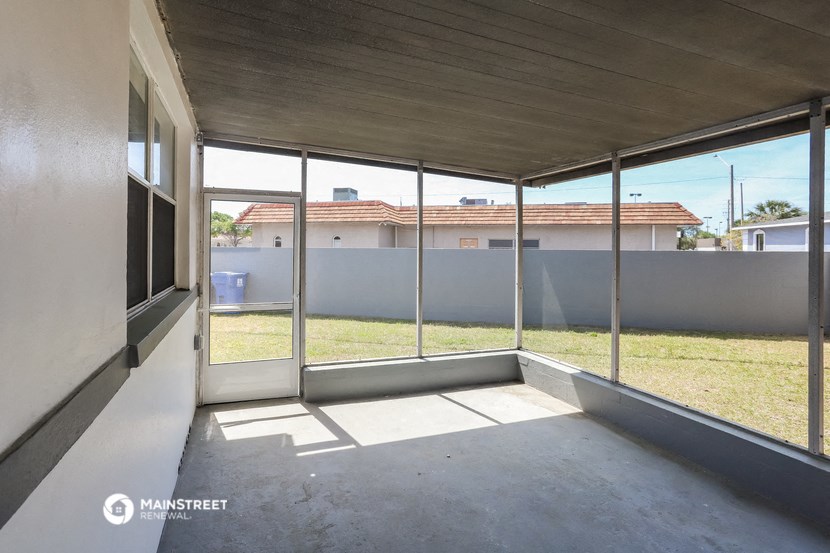 a large porch with glass doors and a view of the grass
