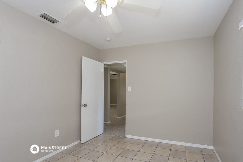 a empty room with a ceiling fan and a door to a hallway