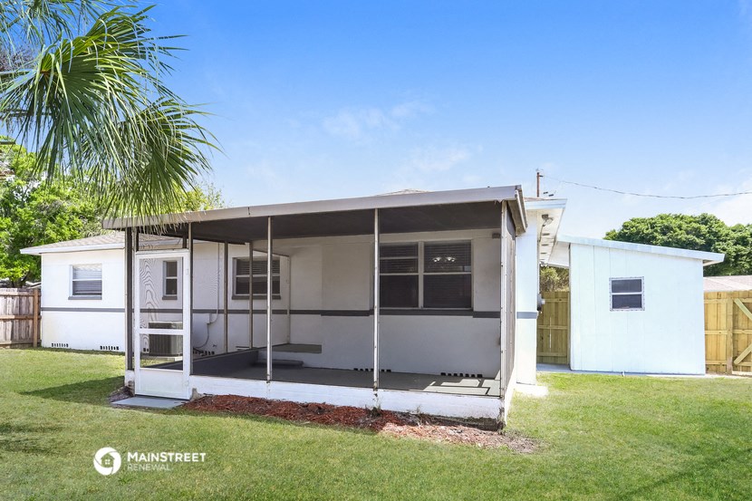 a small white house with a porch and a palm tree