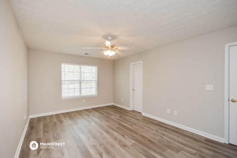 the spacious living room with hardwood flooring and a ceiling fan