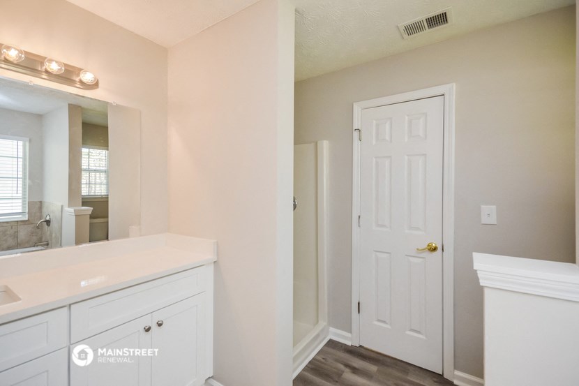 a bathroom with a white door and a sink and a mirror