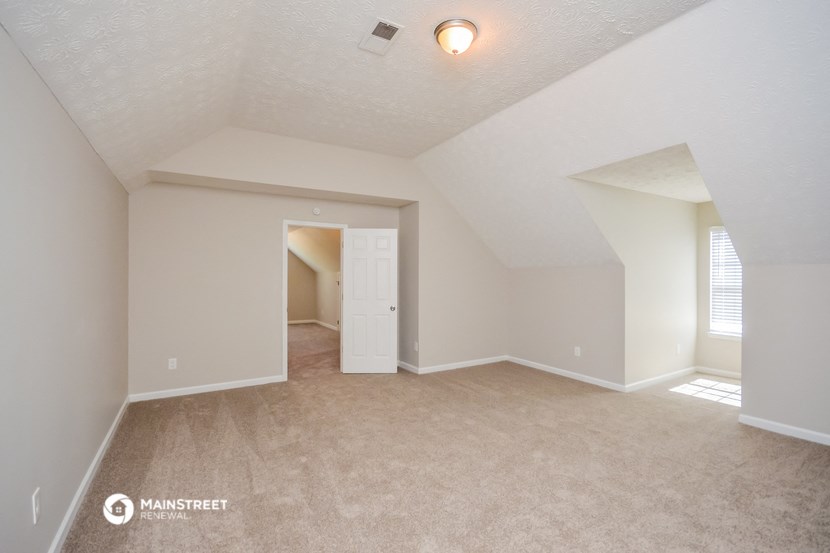 the spacious living room with carpeting and a door to the hallway