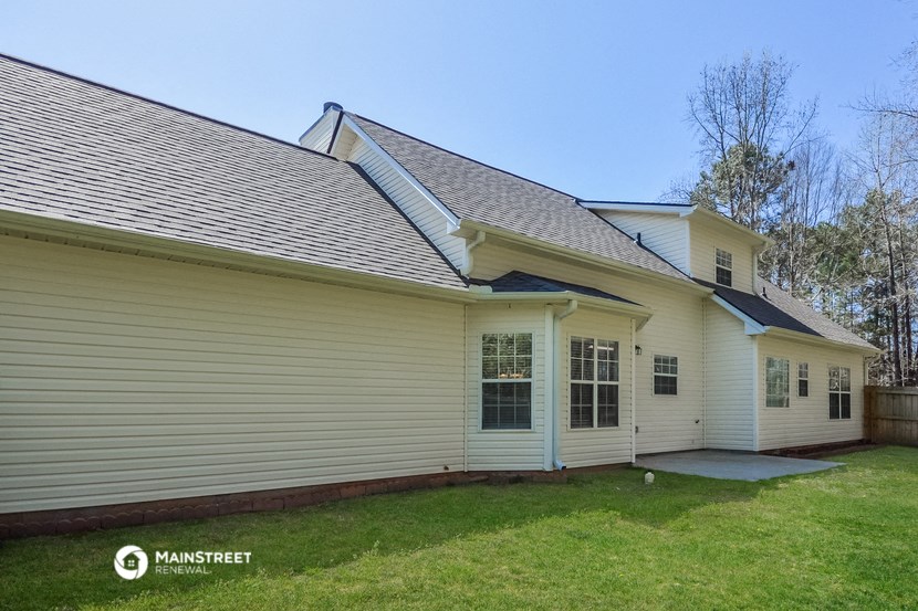 the front of a white house with white siding and a lawn