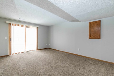 the living room of an empty house with carpet and a window