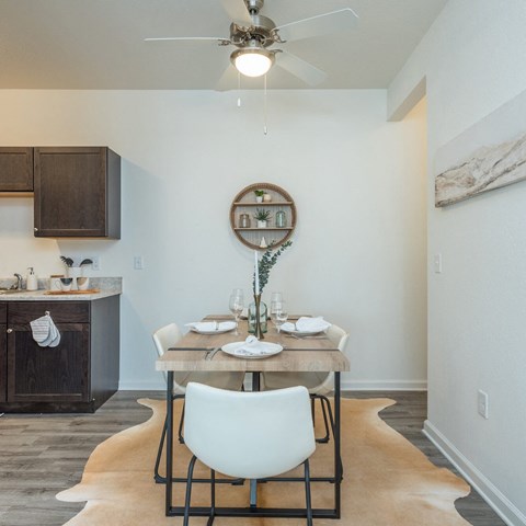 a dining area with a table and chairs and a ceiling fan