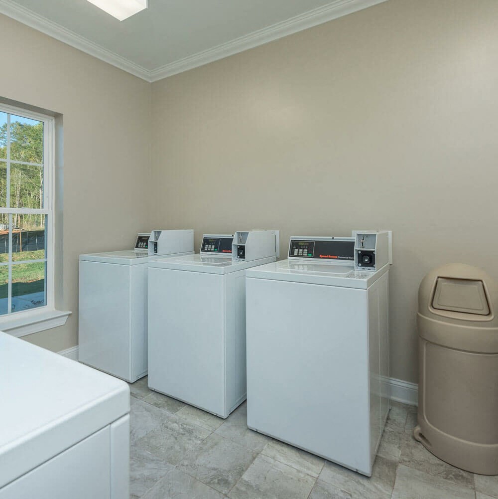 four washers and dryers in a laundry room with a window