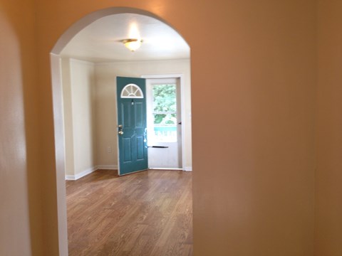 an empty room with a blue door and wood floors