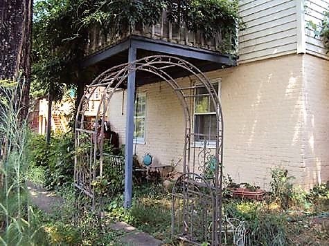A house with a porch covered in vines.