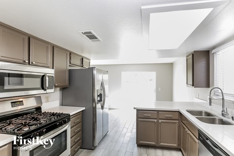 A modern kitchen with a stove top oven, refrigerator, and sink.