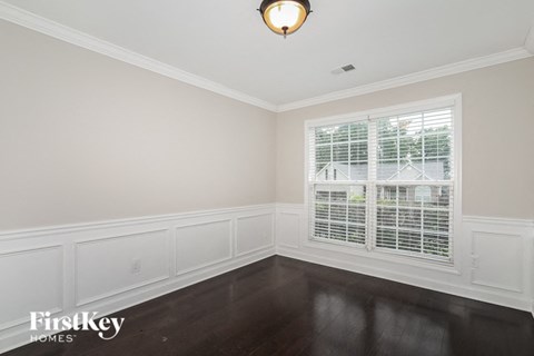 an empty room with a large window and dark wood floors