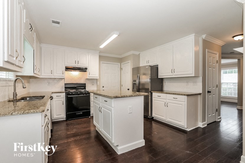 a large kitchen with white cabinets and black appliances
