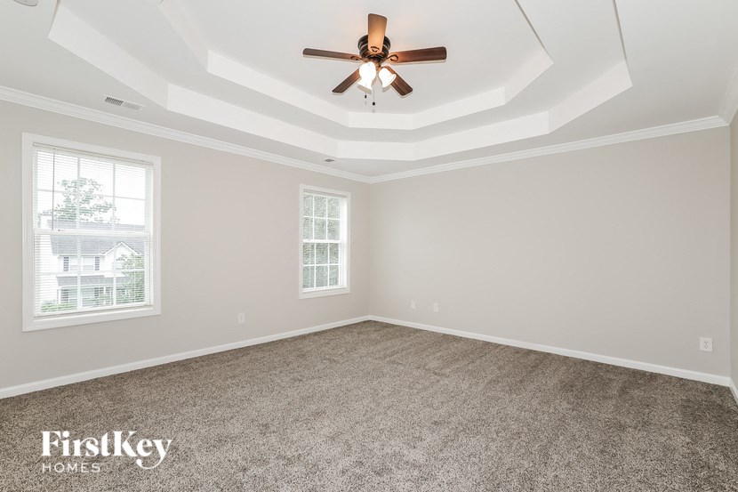 a living room with a ceiling fan and a carpet
