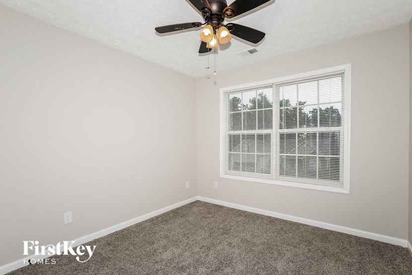 an empty bedroom with a ceiling fan and a window