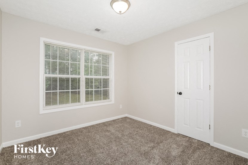 an empty bedroom with a white door and a window
